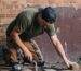 an image of a worker kneeling doing brick paver work to fix a sidewalk
