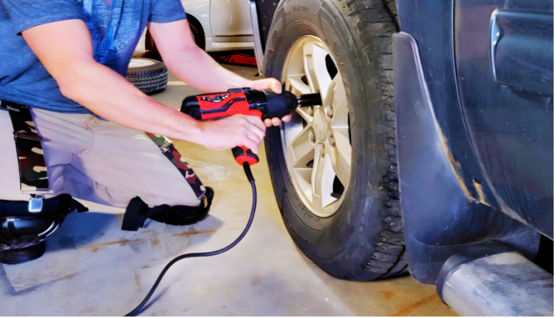 a mechanic kneeling to work on a truck tire while wearing knee pad hangers to hold up his knee pads on the job.