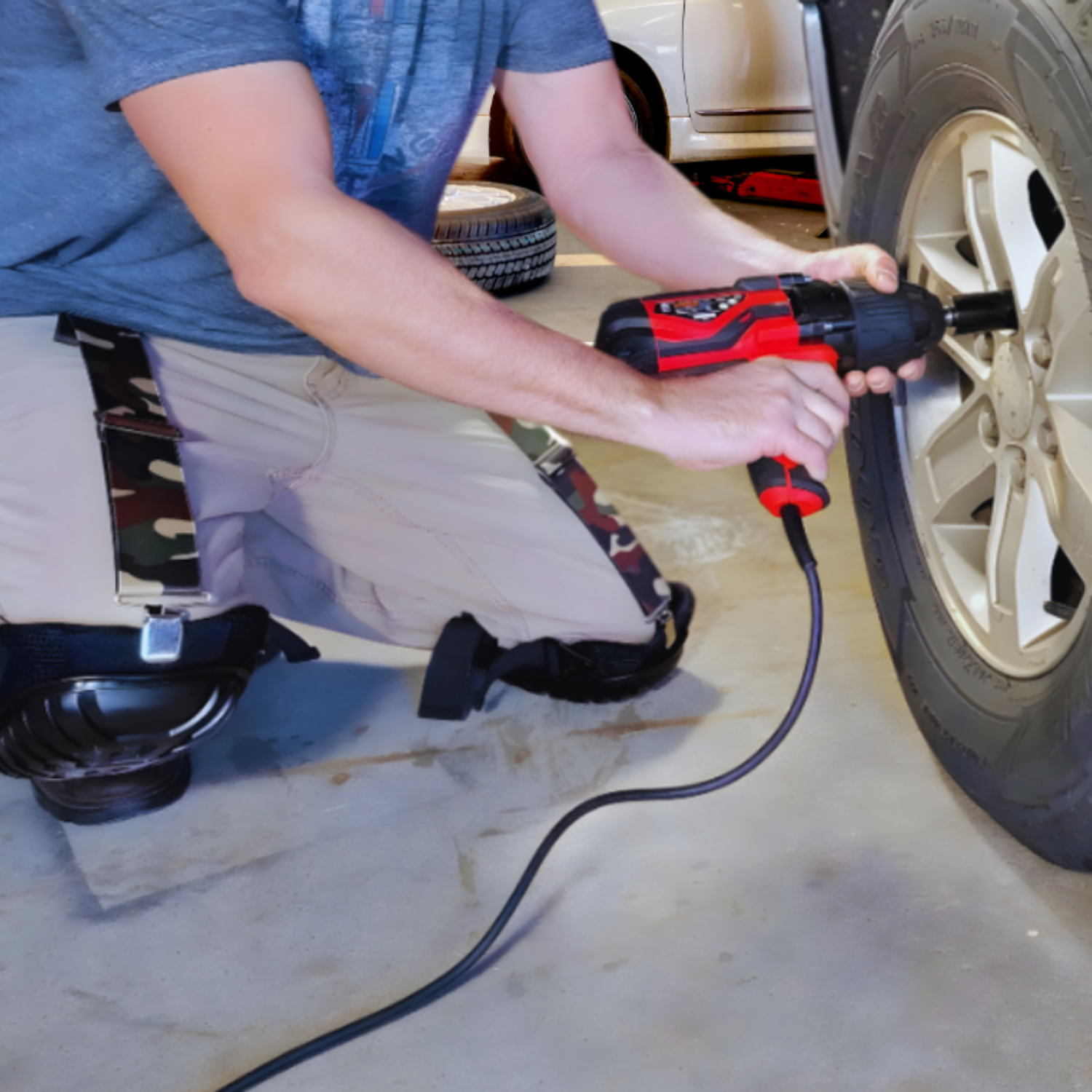 auto mechanic working on a truck wearing knee pads while using a pair of knee pad hangers to hold up his knee pads